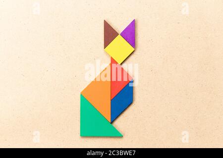 Color tangram puzzle in sitting cat shape on wood background Stock Photo