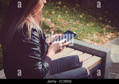 E-lerning in the park. Female student is preparing for her exams while siting on the parkbench Stock Photo