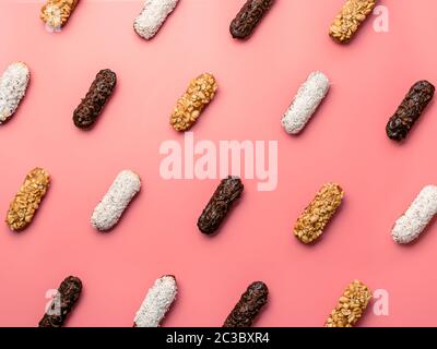 Pattern of different homemade eclairs on pink background. Top view of delicious healthy profitroles with different decor - chocolate, peanut and sherd Stock Photo