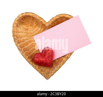 Close up one red painted natural wooden carved heart over pink paper envelope in heart shaped bowl isolated on white background Stock Photo