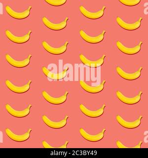 Seamless pattern of fresh ripe yellow bananas on coral pink background Stock Photo