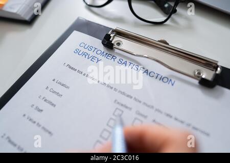 Close-up Of Woman's Hand Filling Customer Survey Form Stock Photo