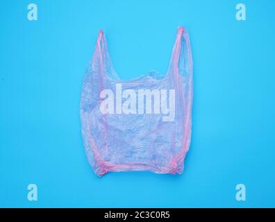open empty plastic pink bag for products on a blue background, concept of rejection of plastic bags to save the environment Stock Photo