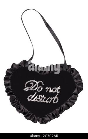 Close-up of a heart-shaped pendant made of black fabric with the inscription Do Not Disturb, isolated on a white background. Wedding concept. Macro ph Stock Photo