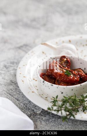 sun-dried tomatoes in a plate on a light concrete background. Stock Photo