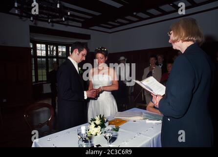 Bride and Groom In Their Twenties Exchanging Vows and Groom Placing Ring on Brides Finger Stock Photo