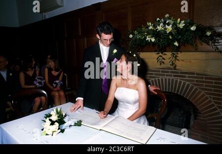 Bride and Groom in their Twenties Signing the Register at Wedding Stock Photo