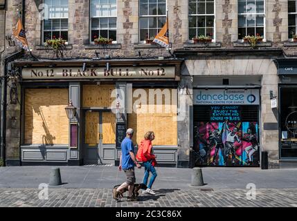 Edinburgh, Scotland, United Kingdom, 19th June 2020. Black Lives Matter Mural Trail: a new trail of artwork is developing at arts venues to support the BLM campaign initiated by arts producer Wezi Mhura. Pictured: artwork by the Graffiti Collective at Dancebase and the boarded up Black Bull pub in the Grassmarket as a couple walks past Stock Photo