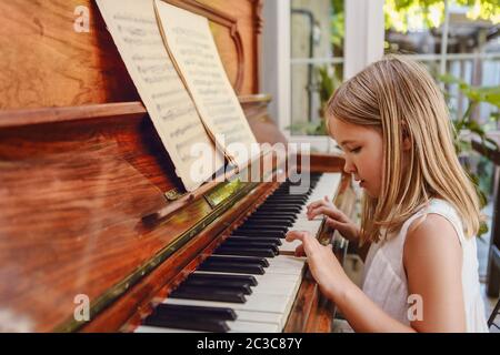 Talented little girl playing piano in modern living room Stock Photo