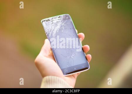 young man hold broken smartphone screen. Broken phone screen in hand Stock Photo