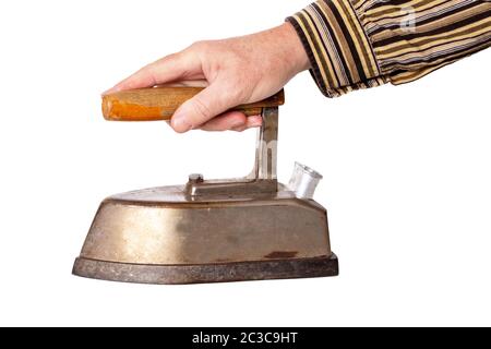 Vintage ironing tool household. Hand of a man, hold an old rusty professional electric tailor iron at the wooden handle, is isolated on a white backgr Stock Photo