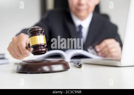 Male Judge lawyer In A Courtroom Striking The Gavel on sounding block. Stock Photo