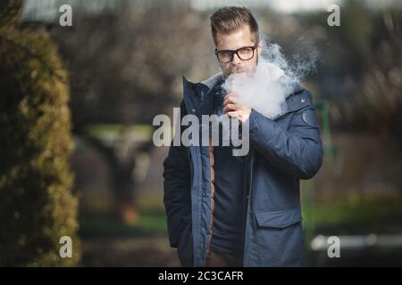 Vaping flavored e-liquid from an electronic cigarette Stock Photo