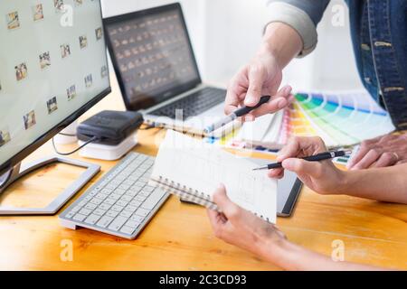 young couple sitting at the table and working together of creative designers working at the studio doing some retouching on a creative project. Stock Photo