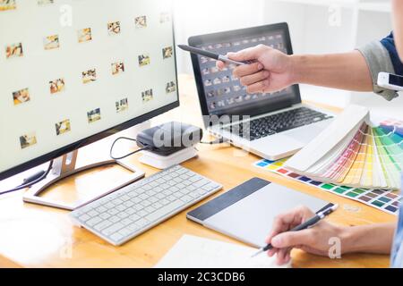 graphic designer team working on web design using color swatches editing artwork using tablet and a stylus At Desks In Busy Creative Office Stock Photo