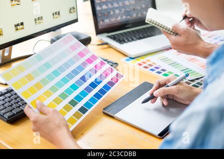young couple sitting at the table and working together of creative designers working at the studio doing some retouching on a creative project. Stock Photo