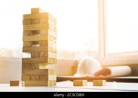 the blocks wood tower game with architectural engineer plans or blue prints compasses ,pencils and ruler on wooden table, plan and building concept. Stock Photo