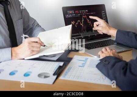 Businessmen talking about stock market invest trading online analysis discussing financial graph  for investment purposes discussion in traders office Stock Photo