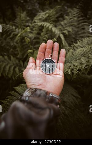 Close up of explorer male holding a compass in green rainy forest.Survival travel,lifestyle concept Stock Photo