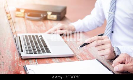 Two businessmen discussing planing tasks with laptop computer sitting at outdoor table. Stock Photo
