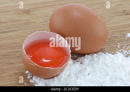 Two eggs and flour on a wood surface Stock Photo