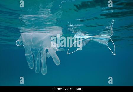 Face mask and gloves float under water surface in the sea, plastic waste pollution since coronavirus COVID-19 pandemic
