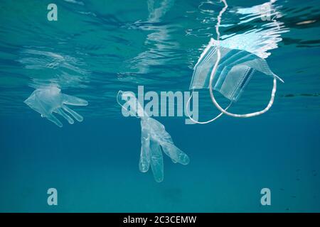 Face mask and gloves underwater in the ocean, plastic waste pollution in the water since coronavirus COVID-19 pandemic