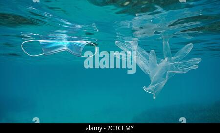 Face mask and transparent gloves underwater, plastic waste pollution in the sea since coronavirus COVID-19 pandemic Stock Photo