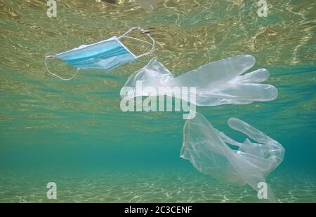 Gloves and face mask in the ocean, plastic waste pollution underwater since coronavirus COVID-19 pandemic