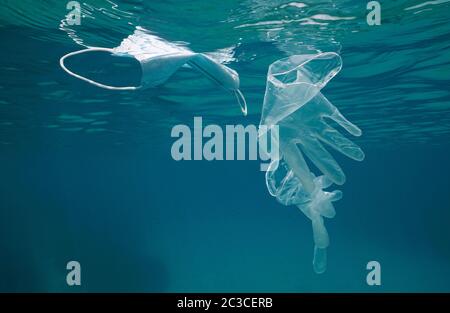 Gloves and face mask underwater in the sea, plastic waste pollution since coronavirus COVID-19 pandemic