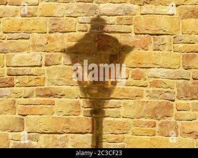 Closeup photo of an illuminated orange-yellow brick wall with a falling shadow from a lantern on it Stock Photo