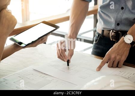 Two Architects engineer discussing  data working and tablet, laptop with blueprint - Closeup on hands and project print. Stock Photo