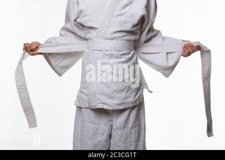 Stages of correct tying of the belt by a teenager on a sports kimono, step four Stock Photo