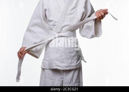 Stages of correct tying of the belt by a teenager on a sports kimono, step seven Stock Photo