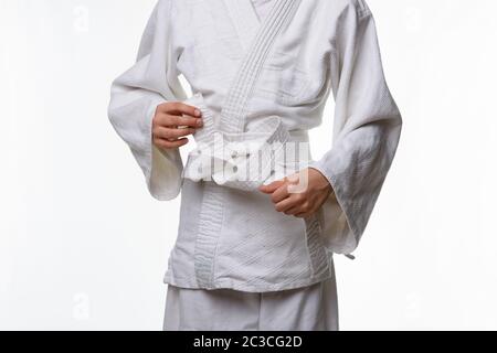 Stages of correct tying of the belt by a teenager on a sports kimono, step eight Stock Photo