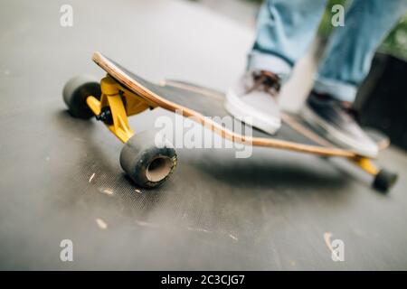 Close up of unrecognizable young man riding longboard outdoors in skateboarding park, copy space Stock Photo