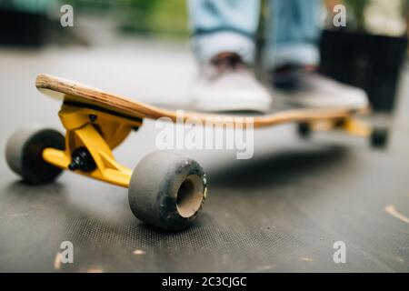 Close up of unrecognizable young man riding longboard outdoors in skateboarding park, copy space Stock Photo