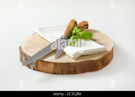 Set of two sharp pointed tip kitchen knives and white napkin on round wood slab Stock Photo