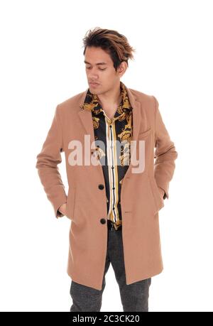A tall young handsome man standing with his hands in his coat pocket looking down, isolated for white background Stock Photo