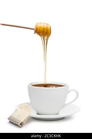 Honey dripping into cup of tea, on white background Stock Photo