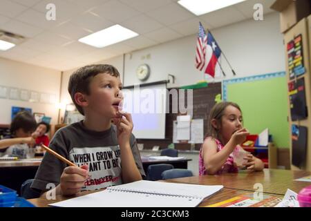 Austin Texas USA, 2013: 8 year old Mexican-American boy writes on notebook with a pencil in first-grade public elementary school classroom. ©Marjorie Kamys Cotera/Daemmrich Photography Stock Photo
