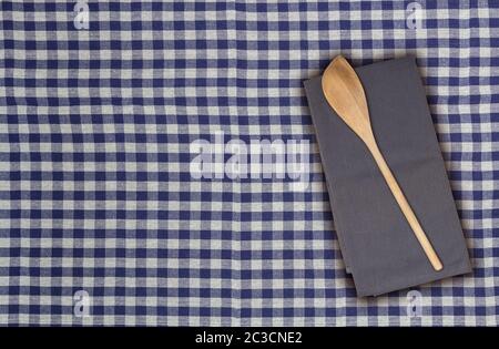 Wooden spoon and kitchen towel on blue white checkered kitchen towel. Stock Photo