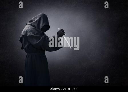 Hooded man with dagger in the dark Stock Photo