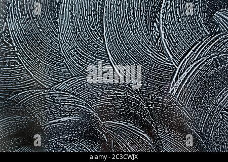 Abstract background. Swirling soap sud foam pattern on window with dark background.