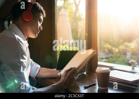 Focused asian college student working with laptop in cafe preparing for test or exam. Stock Photo