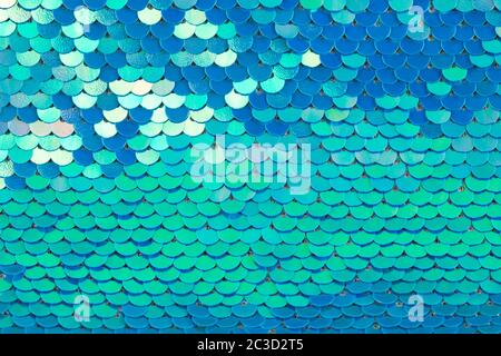 Abstract textured holographic background from turquoise shiny iridescent sequins, like mermaid or fish scales. Trendy texture with copy space. Celebra Stock Photo