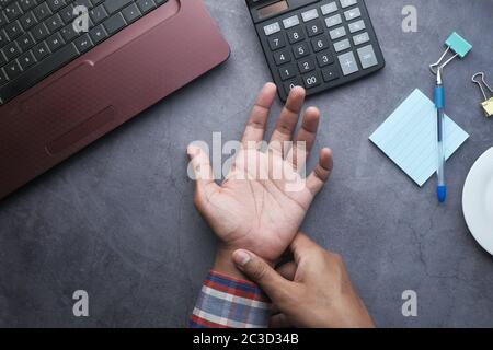 Young man in blue shirt suffering wrist pain  Stock Photo