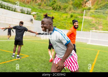 Barcelona, spain - 10 june 2020: portrait of young african black immigrant man playing soccer in team, smiling and enjoying together with teammates in Stock Photo