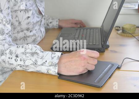 Graphic designer working on digital tablet. The workplace of the designer, men's hands work on a graphics tablet. Close-up. Home office Stock Photo
