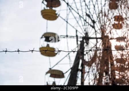 barbed wire and cabins carousel wheel in an abandoned amusement park in Chernobyl Stock Photo